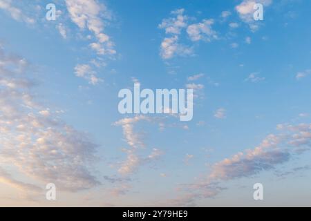 Ein klarer blauer Himmel mit Licht, verstreute kleine Wolken am Morgen, die sich über den Horizont erstrecken. Der Himmel wird durch sanftes Morgenlicht beleuchtet, wodurch ein sl entsteht Stockfoto