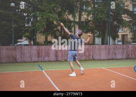 Der Badmintonspieler schlägt während eines Spiels auf einem Platz im Freien den Shuttlecock und zeigt dabei präzise Technik und sportliche Bewegung. Der Spieler fokussiert ist, Stockfoto