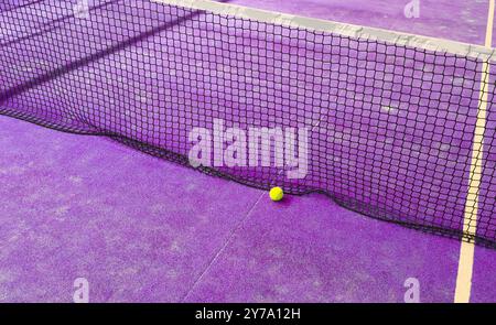 Ball im Schatten des Netzes eines blauen Paddle-Tennisplatzes. Stockfoto