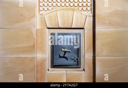 Die Tür eines alten Ofens, in den Feuerholz gelegt wurde. Stockfoto
