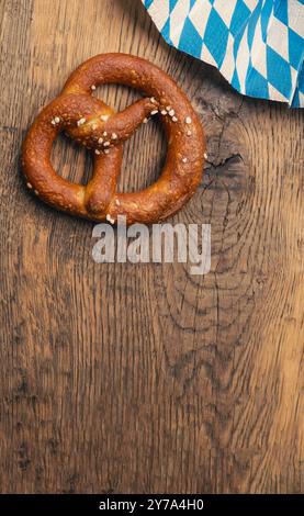 Leckere Brezel mit bayerischer Flagge auf einem rustikalen Holztisch, Oktoberfest oder traditionelles bayerisches Speisekonzept Stockfoto