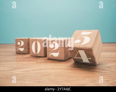 Holzblöcke mit der Jahreszahl 2025 auf blauem Hintergrund, Neujahrskonzept, saisonale Weihnachtszeit Stockfoto