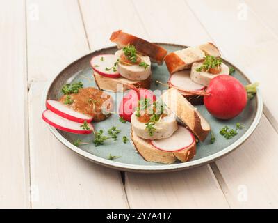 Weißwurst mit süßem Senf und Brezel, serviert als Fingerfood auf einem hölzernen Küchentisch Stockfoto