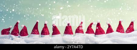 Viele Hüte von Santa in einer Reihe mit Schnee, Weihnachten Hintergrund, Panoramaaussicht Stockfoto