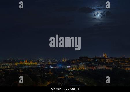 „Ein rätselhaftes, dunkles Stadtbild von Budapest mit einem von Wolken bedeckten Mond und einem tiefblauen Himmel Stockfoto