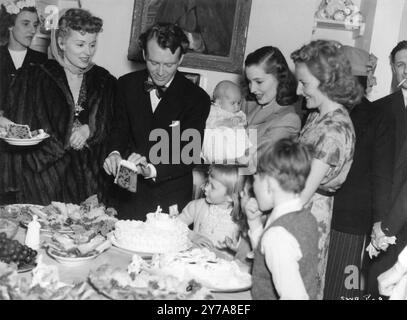 Der britische Schauspieler JOHN MILLS schneidet den Kuchen auf der Party nach der Taufe der Tochter HAYLEY MILLS in Denham Village im Jahr 1946. Von links nach rechts: MARTHA SCOTT, JOHN MILLS, VALERIE HOBSON (Holding Hayley), JULIET MILLS und MARY HAYLEY BELL. Veröffentlicht als Werbung für SO WELL REMEMBER 1947 Alliance Productions / RKO Radio Briitish Productions Stockfoto