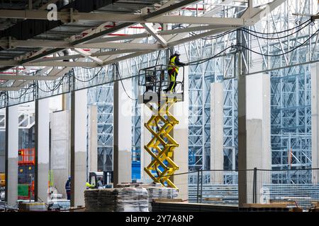 Elektriker, die Kabel an Kabeltrassen installieren, die in der Höhe auf der Baustelle arbeiten Stockfoto