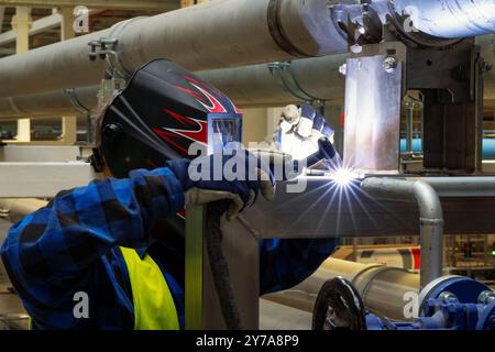 Schweißerschweißen von Stahlelementen mit WIG-MIG-Verfahren im Innenbereich in Schutzeinrichtungen im industriellen Umfeld Stockfoto