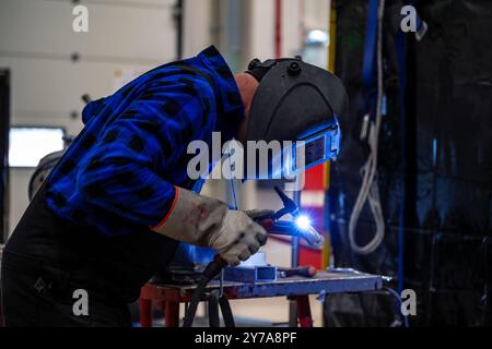 Schweißerschweißen von Stahlelementen mit WIG-MIG-Verfahren im Innenbereich in Schutzeinrichtungen im industriellen Umfeld Stockfoto