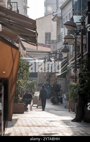 Limassol, Zypern - 26. Januar 2023: Menschen gehen auf der leeren Straße in Limassol mit geschlossenen Geschäften und Cafés tagsüber Stockfoto