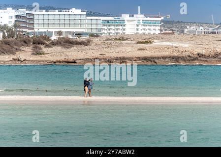 Ayia Napa, Zypern - 25. März 2022: Zwei Frauen laufen auf einer Sandbank am Strand von Nissi Stockfoto