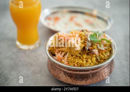 Würziger indischer Biryani-Pulao in goldener Schüssel mit indischem Basmati-Reisgericht mit Hühnerfleisch-Curry Ramadan Kareem, Eid. Servierschale aus Messing mit weißem Rücken Stockfoto