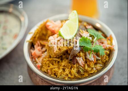 Würziger indischer Biryani-Pulao in goldener Schüssel mit indischem Basmati-Reisgericht mit Hühnerfleisch-Curry Ramadan Kareem, Eid. Servierschale aus Messing mit weißem Rücken Stockfoto