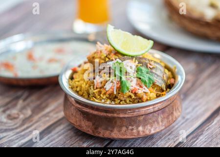 Würziger indischer Biryani-Pulao in goldener Schüssel mit indischem Basmati-Reisgericht mit Hühnerfleisch-Curry Ramadan Kareem, Eid. Servierschale aus Messing mit weißem Rücken Stockfoto