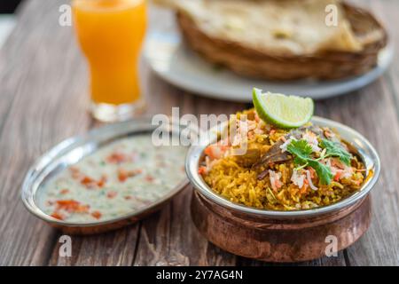 Würziger indischer Biryani-Pulao in goldener Schüssel mit indischem Basmati-Reisgericht mit Hühnerfleisch-Curry Ramadan Kareem, Eid. Servierschale aus Messing mit weißem Rücken Stockfoto