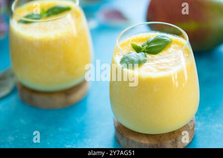 Frische Mangolassi in Gläsern auf blauem Hintergrund mit Kopierraum. Indischer gesunder detoxic ayurvedischer Kaltwasser mit Mango. Frische Lassi aus Yogur Stockfoto