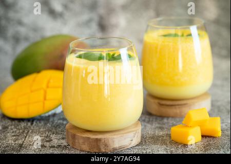 Frische Mangolassi in Gläsern auf grauem Hintergrund mit Kopierraum. Indischer gesunder detoxic ayurvedischer Kaltwasser mit Mango. Frische Lassi aus Yogur Stockfoto