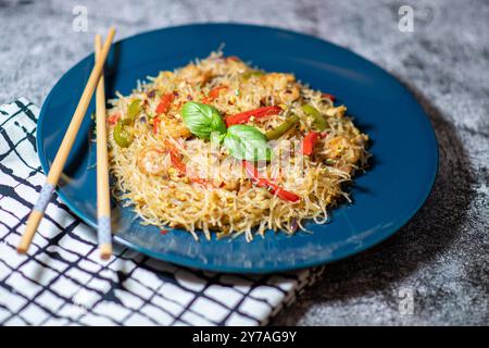 Asiatischer Salat mit Glasnudeln, Huhn, Garnelen, Garnelen und Gemüse auf grauem Hintergrund. Nahaufnahme mit Stäbchen. Ausgewählter Fokus mit frischem Gemüse Stockfoto