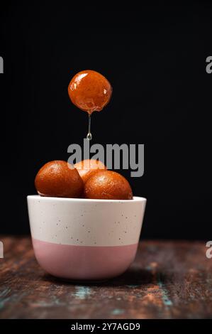 Gulab Jamun serviert in einer Schüssel mit süßem Sirup. Gulab Jamun ist eine indische Süßigkeit auf Milchbasis, die auf Festivals oder Hochzeitsfeiern hergestellt wird Stockfoto