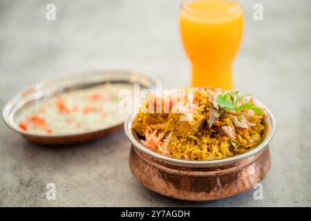 Würziger indischer Biryani-Pulao in goldener Schüssel mit indischem Basmati-Reisgericht mit Hühnerfleisch-Curry Ramadan Kareem, Eid. Servierschale aus Messing mit weißem Rücken Stockfoto