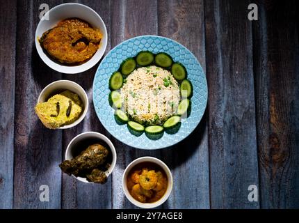 Verschiedene indische Essensdekorationen auf dunklem Holzhintergrund. Gerichte und Vorspeisen der indischen Küche. Fischcurry, Butterhähnchen, Reisschalen und pla Stockfoto