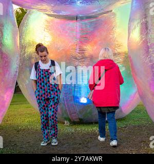 Bournemouth, Dorset, England, Vereinigtes Königreich, 28. September 2024. Arts by the Sea Festival. Zwei Frauen laufen unter einer riesigen Ballonstruktur Verwöhnend von Atelier Sisu. Quelle: Paul Biggins/Alamy Live News Stockfoto