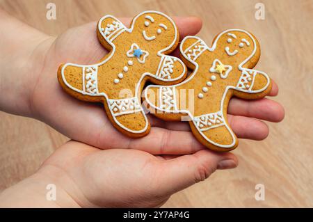 Zwei Lebkuchenmännchen Kekse mit weißer Glasur in den Händen, bereit für die Weihnachtsfeier. Stockfoto