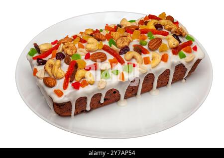Weihnachtsgebäck mit weißer Glasur, garniert mit getrockneten Früchten und Nüssen auf einer weißen Platte. Stockfoto