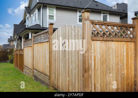 Großer neuer Holzzaun um das Haus und die Bäume. Harter Holzzaun mit grünen Bäumen und Weg. Zäune und Tore. Hochwertiger Zaun. Straßenfoto. Stockfoto