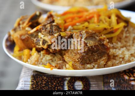 Traditionelle usbekische orientalische Küche, Pilaw oder Plov mit großen Fleischstücken und Karotten, zubereitet in einer schwarzen gusseisernen Pfanne aus kasan. Selektiver Fokus Stockfoto