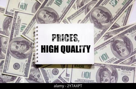 Auf einem Notizblock liegen die Textpreise, hohe Qualität, Dollar auf weißem Hintergrund, Finanzkonzept, Qualität, Service, Kundenzufriedenheit Stockfoto
