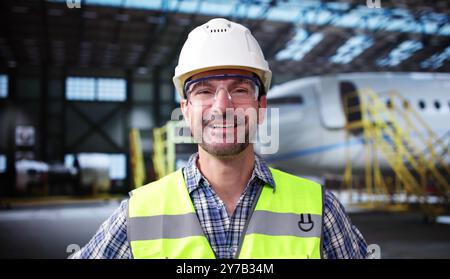 Luftfahrzeugtechniker Porträt Am Flughafen-Hangar Mit Flugzeug Stockfoto