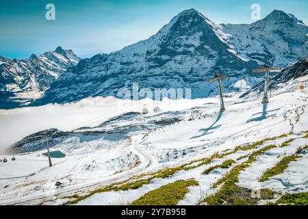 Eines der berühmtesten Skigebiete mit Seilbahnen auf der Piste und hohen schneebedeckten Bergen im Hintergrund, Mannlichen Bahnhof, Grindelwald, Berner Oberla Stockfoto