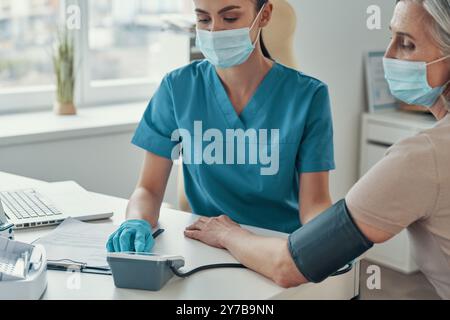 Junge Rettungssanitäterin mit Überwachungsgeräten zur Kontrolle des Reifen Frauenpulses während der Arbeit im Krankenhaus Stockfoto