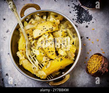 Indisches Curry aus Kartoffeln und Kohl in einer Kupferschüssel auf Metall-Hintergrund. Draufsicht. Selektiver Fokus Stockfoto