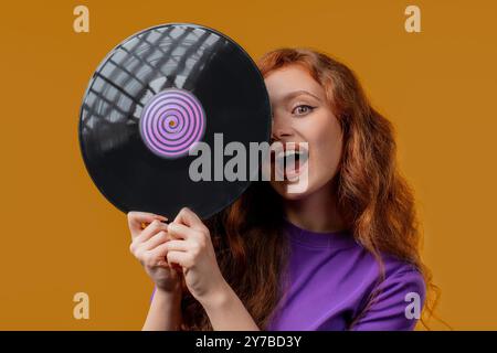 Hübsche Frau tanzt mit Schallplatte auf Gelb. Hobby, Musikliebhaber, Sammlung, Nostalgie Lifestyle. Hohe Qualität Stockfoto