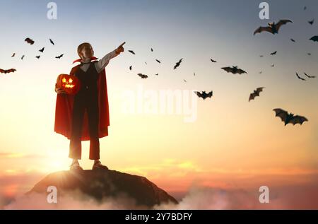 Kleines Kind im Vampirkostüm an Halloween. Junge auf Sonnenuntergang Himmel Hintergrund. Stockfoto