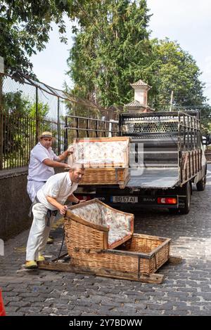 Urlauber und Touristen, die Spaß bei einer Fahrt mit traditionellen Korbschlitten in Monte, Funchal auf der portugiesischen Insel Madeira haben Stockfoto