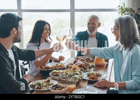 Fröhliche Familie, die mehrere Generationen antost und beim gemeinsamen Abendessen lächelnd ist Stockfoto