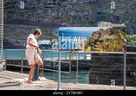 Frau, die ihre Füße bei einer Fahrradwäsche wäscht, nachdem sie am Strand im Ferienort Machico auf der portugiesischen Insel Madeira war Stockfoto