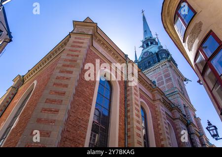 Imposante rote Backsteinfassade mit gotischem Turm vor blauem Himmel. Architektonische Details, historisches Wahrzeichen, Stockholm, Schweden. Stockfoto