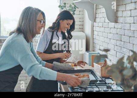 Schöne junge Frau und ihre Mutter kochen zusammen, während sie Zeit in der Hausküche verbringen Stockfoto