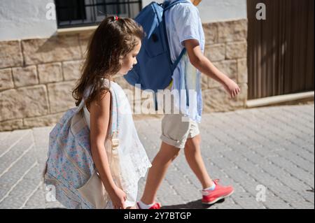 Zwei Kinder laufen an einem sonnigen Tag mit Rucksäcken auf dem Weg zur Schule. Die Szene fängt Jugendliche Energie und den Beginn eines Tages ein. Stockfoto