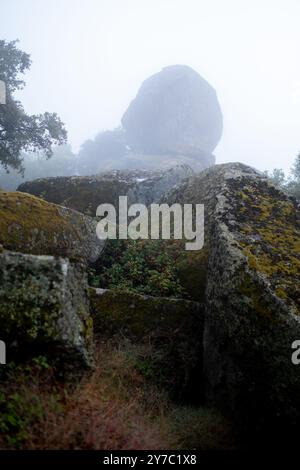 Massive Felsbrocken stehen hoch, während der Nebel in das Tal in Monsanto, Portugal, herabfällt und eine mystische und stimmungsvolle Szene schafft. Stockfoto