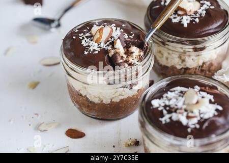 Drei Gläser hausgemachte Schokolade über Nacht Haferflocken mit Kokosnuss und Mandelscheiben. Selektiver Fokus mit verschwommenem Vorder- und Hintergrund. A Stockfoto