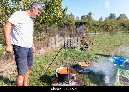 Reifer Mann, der draußen am Lagerfeuer Essen kocht. Stockfoto