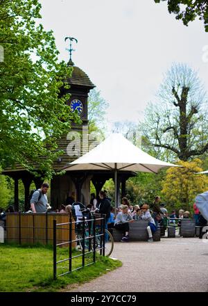 London, England, April 30 2023: Kensington Gardens brechen im Schatten, eine Gruppe von Menschen sitzt unter einem Sonnenschirm Stockfoto