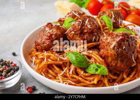 Spaghetti mit Fleischbällchen in Tomatensauce, garniert mit Parmesankäse und frischen Basilikumblättern auf einem Teller. Köstliche italienische Pasta. Leckeres Essen. Nahaufnahme Stockfoto