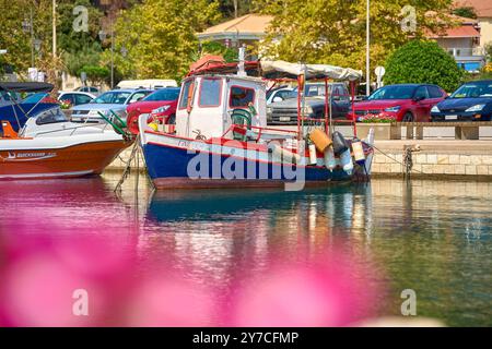 Katakolon, Griechenland - 30. August 2024: Ein traditionelles Fischerboot liegt im Hafen von Katakolon, Griechenland, neben modernen Freizeitbooten, während Autos entlang der Uferpromenade parken *** ein traditionelles Fischerboot liegt im Hafen von Katakolon, Griechenland, neben modernen Freizeitbooten, während Autos entlang der Uferpromenade parken Stockfoto