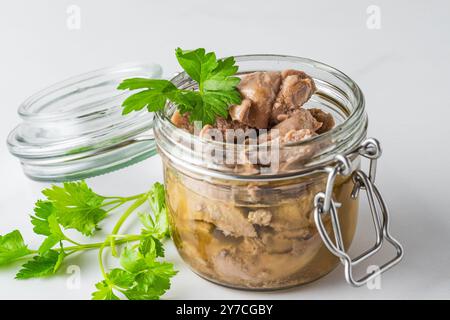 Kabeljauleber in einem Glas mit Petersilie auf weißem Hintergrund. Natürliche Omega-3-Quelle und Vitamin D. Keto-Diätfutter. Nahaufnahme Stockfoto